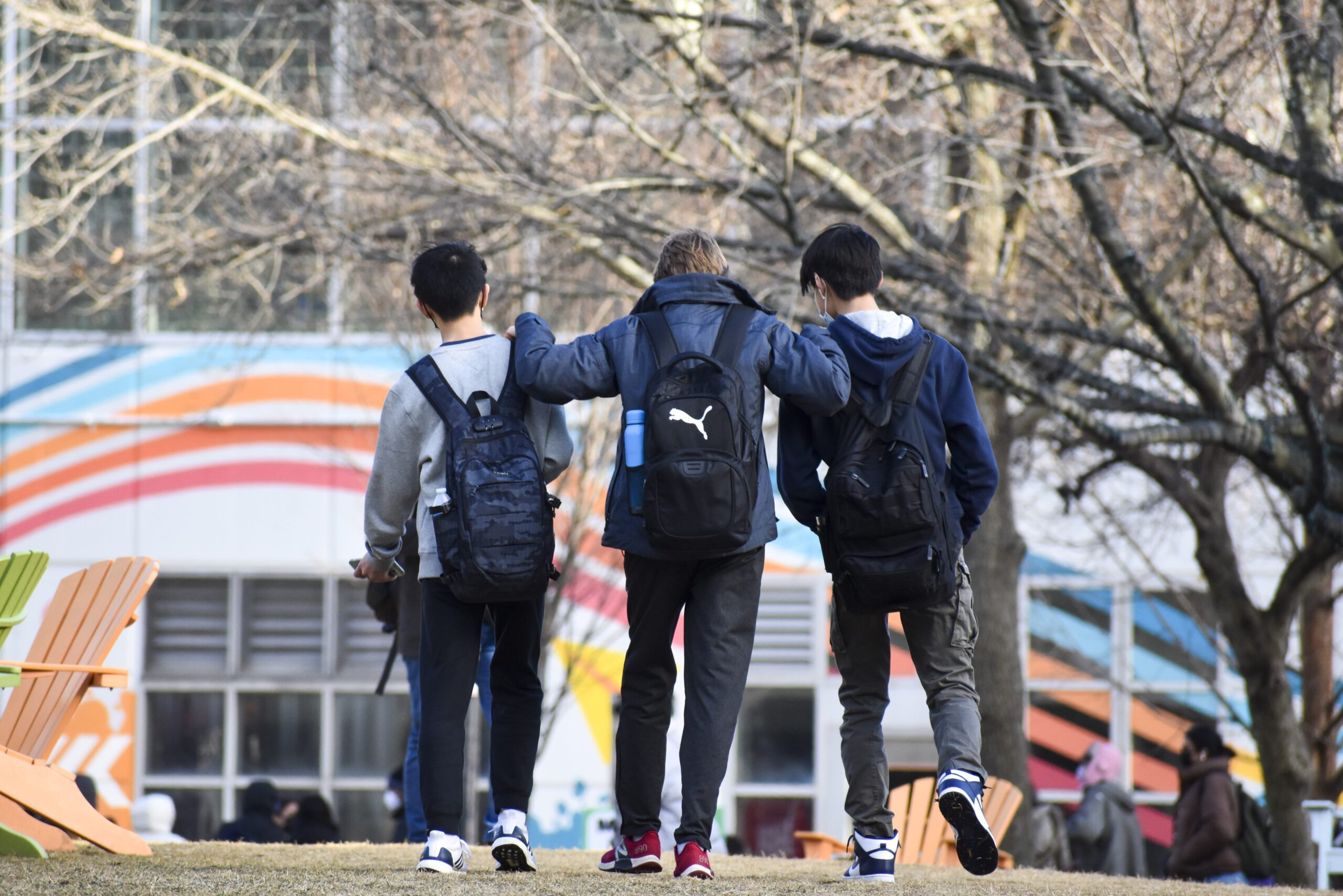 three students walking on campus with they're arms around each other