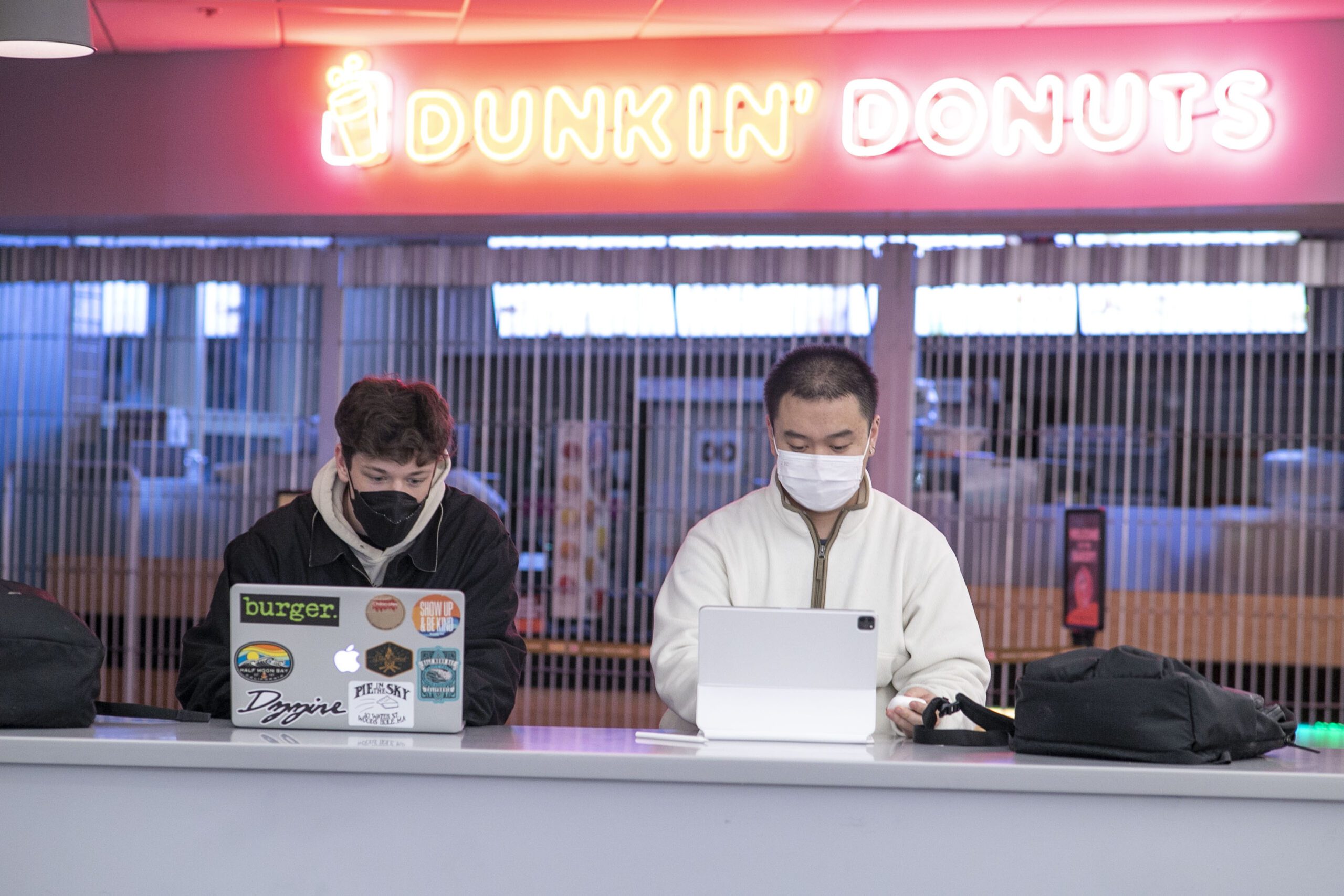 students sitting in front of a dunking donuts cafe doing homework