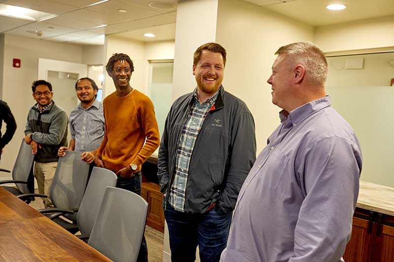 Five people talk around a conference table. Image of SimpliSafe engineers and staff provided by the company.
