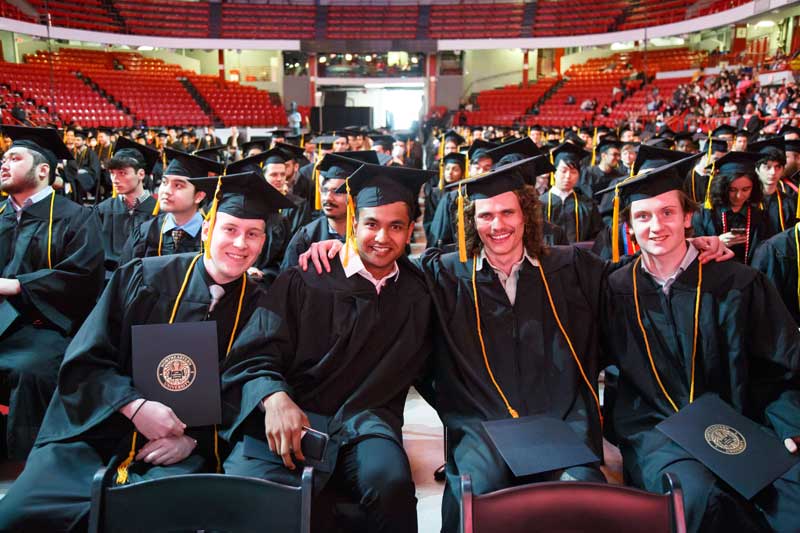 Four Khoury graduates smile for a photo