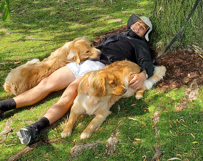 Stephen Alt lays on the ground with his two dogs