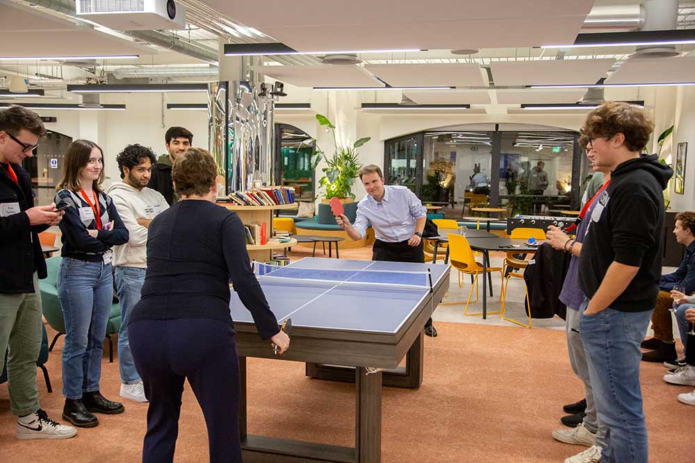 Students watch as Associate Dean of Teaching Faculty Nate Derbinsky plays ping pong with Dean Elizabeth Mynatt on the London campus.