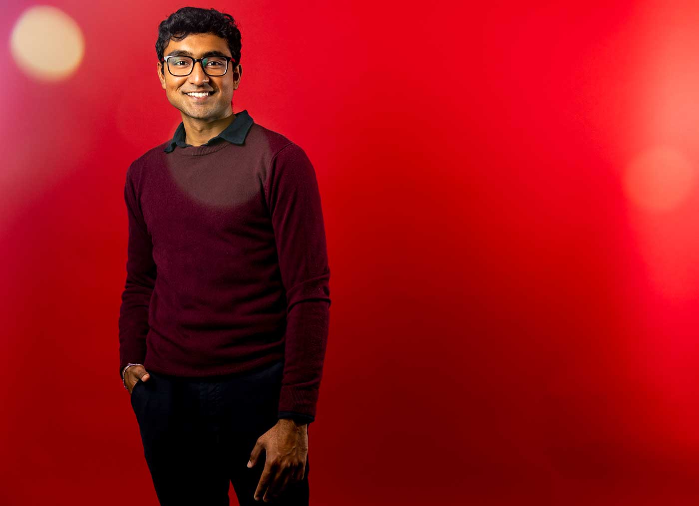 Vivek Kanpa poses in front of a red background