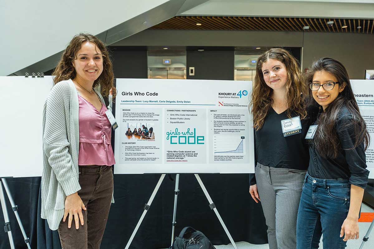 Students in the Girls Who Code club pose in front of their club's poster