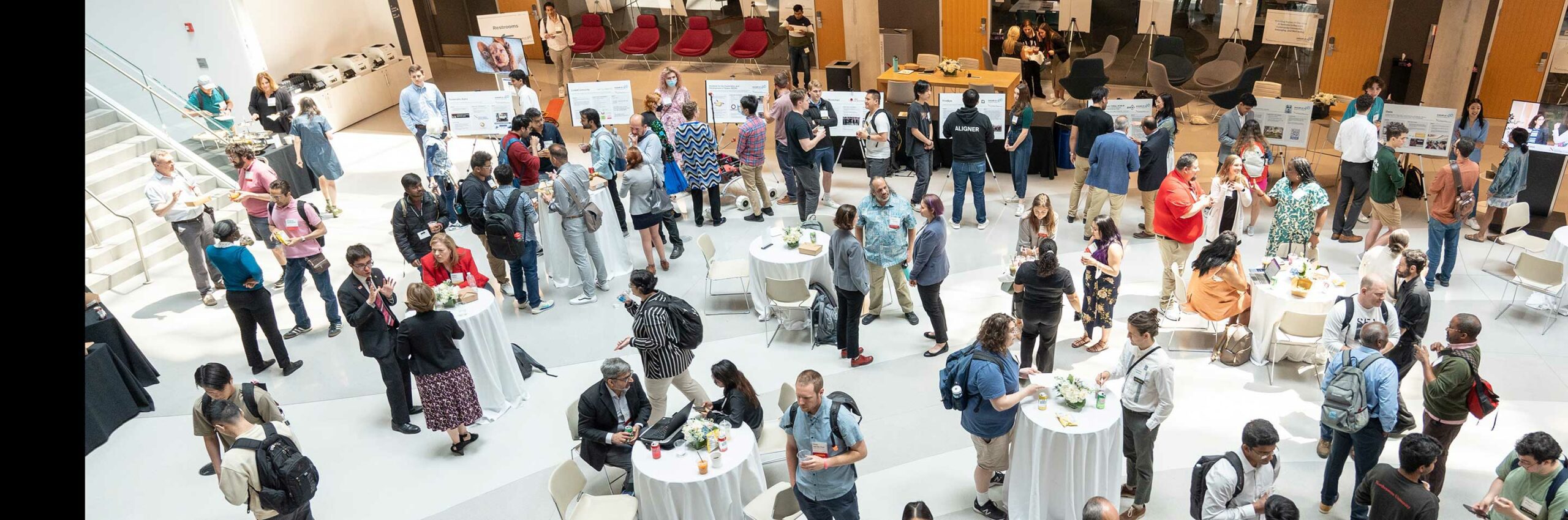 At the Khoury 40th anniversary culmination celebration, guests mingle and discuss research posters in the ISEC atrium