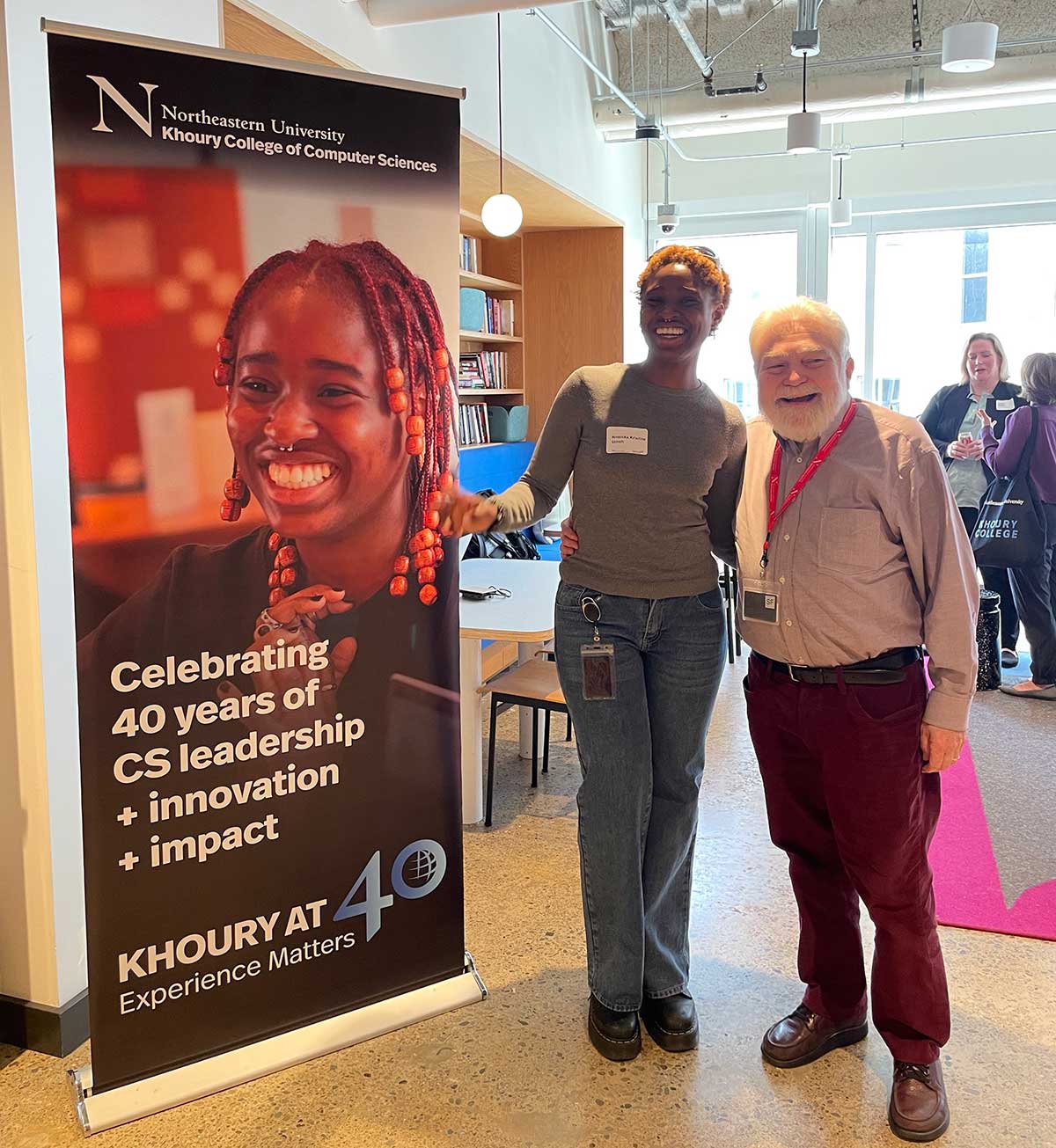 Kristine Umeh (left) and Mark Miller smile next to a banner at the 40th anniversary celebration at the San Francisco campus.
