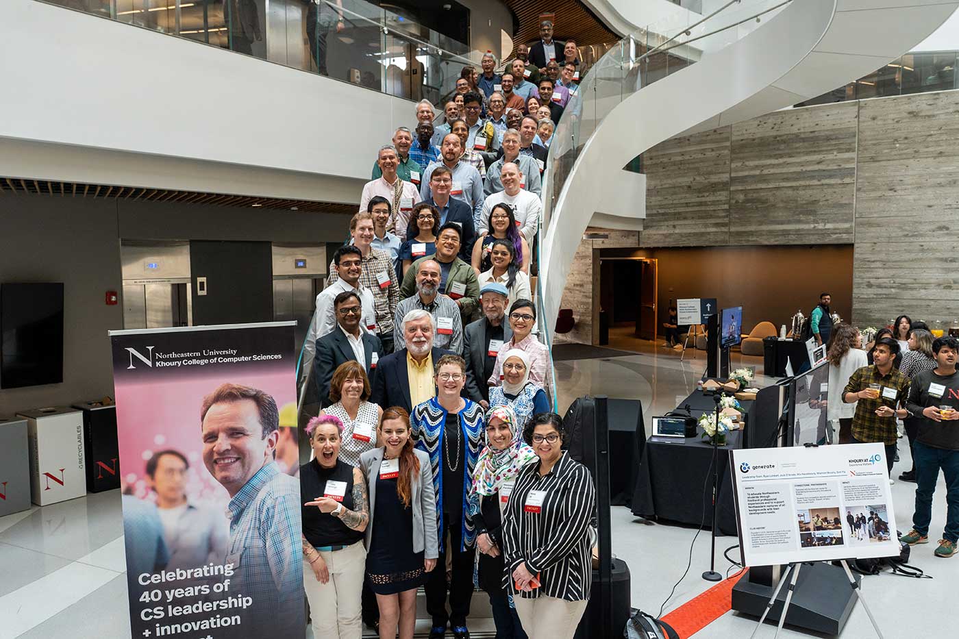 Khoury College faculty gather on the large staircase in the Interdisciplinary Science and Engineering Center. Photo by Ian MacLellan.
