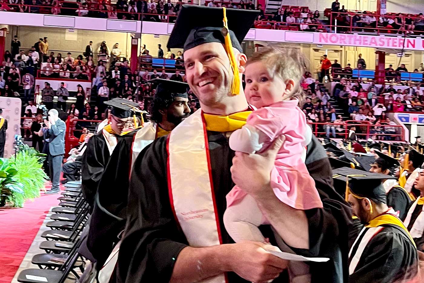 A father holds his child after the graduate recognition ceremony.