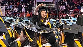 A graduate waves to the crowd during the ceremony