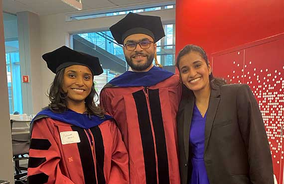 Three PhD graduates smile at the hooding celebration