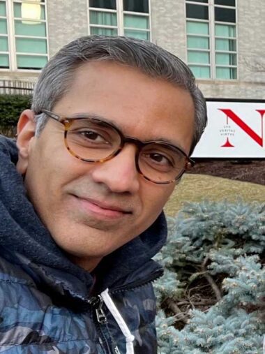Mani Sundaram stands in front of a Northeastern sign
