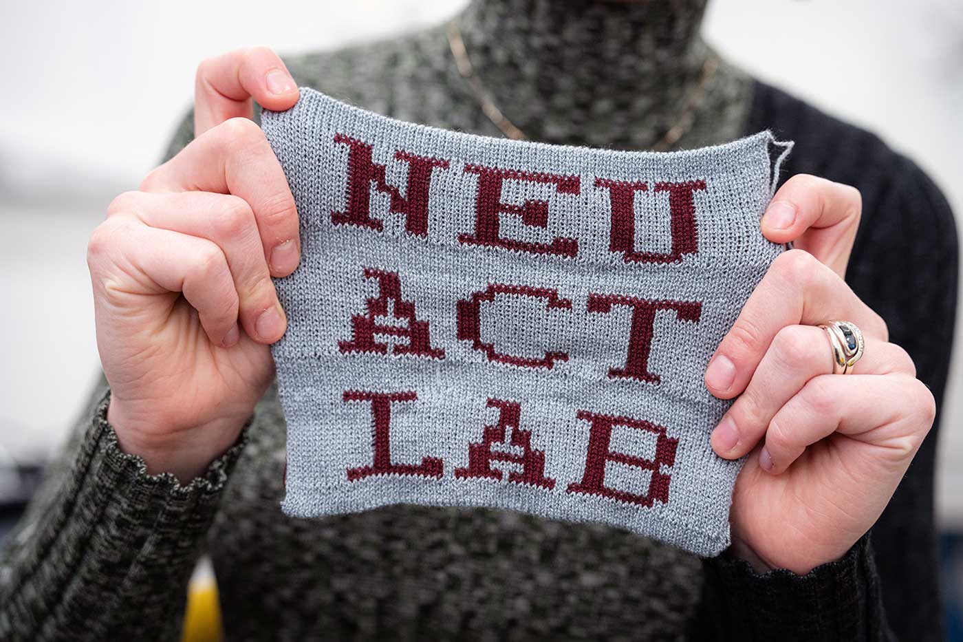 a person holds a piece of fabric that says NEU Act Lab