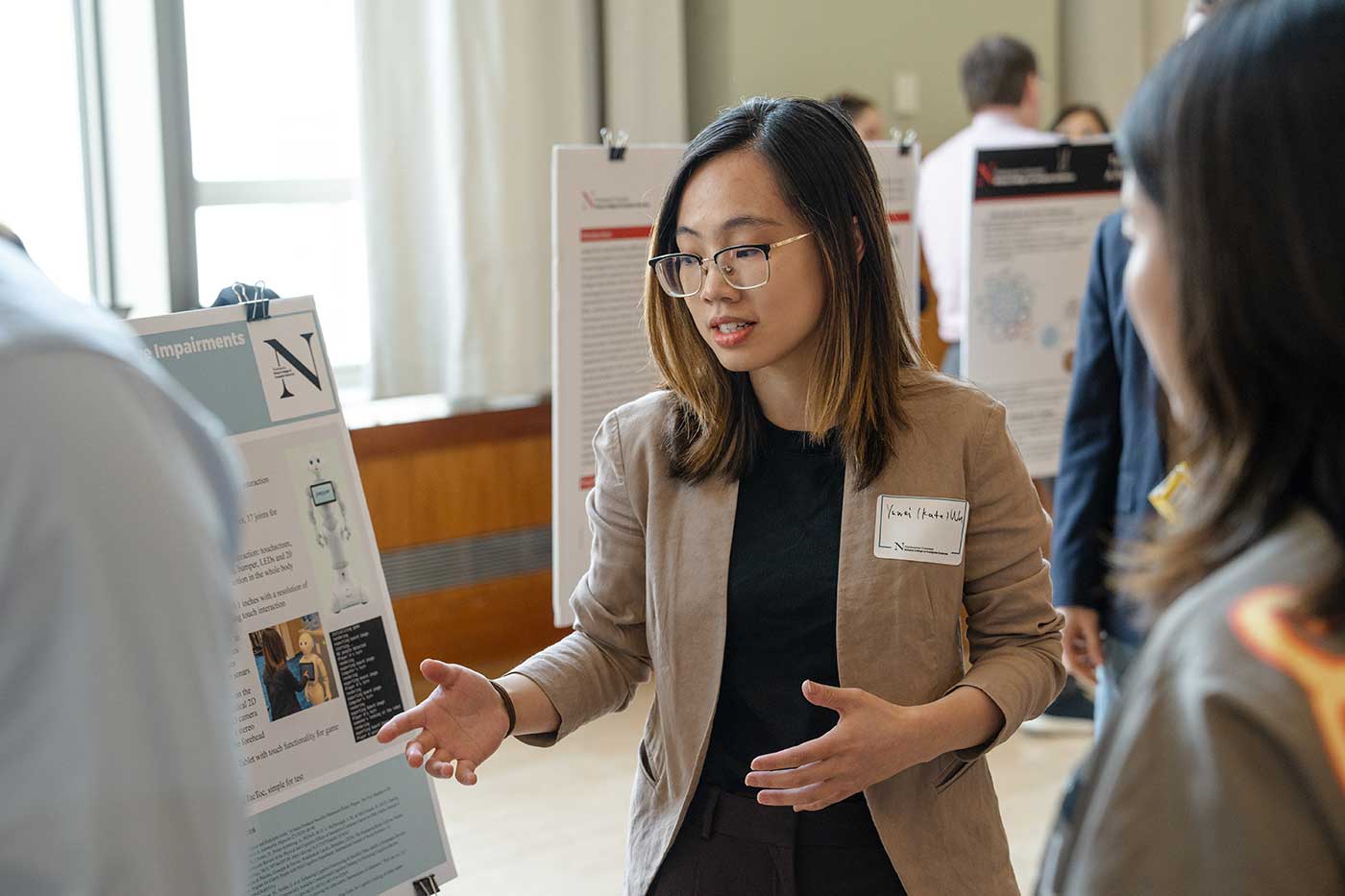 Yuwei (Kate) Wu points at her research poster while talking to two members of the audience
