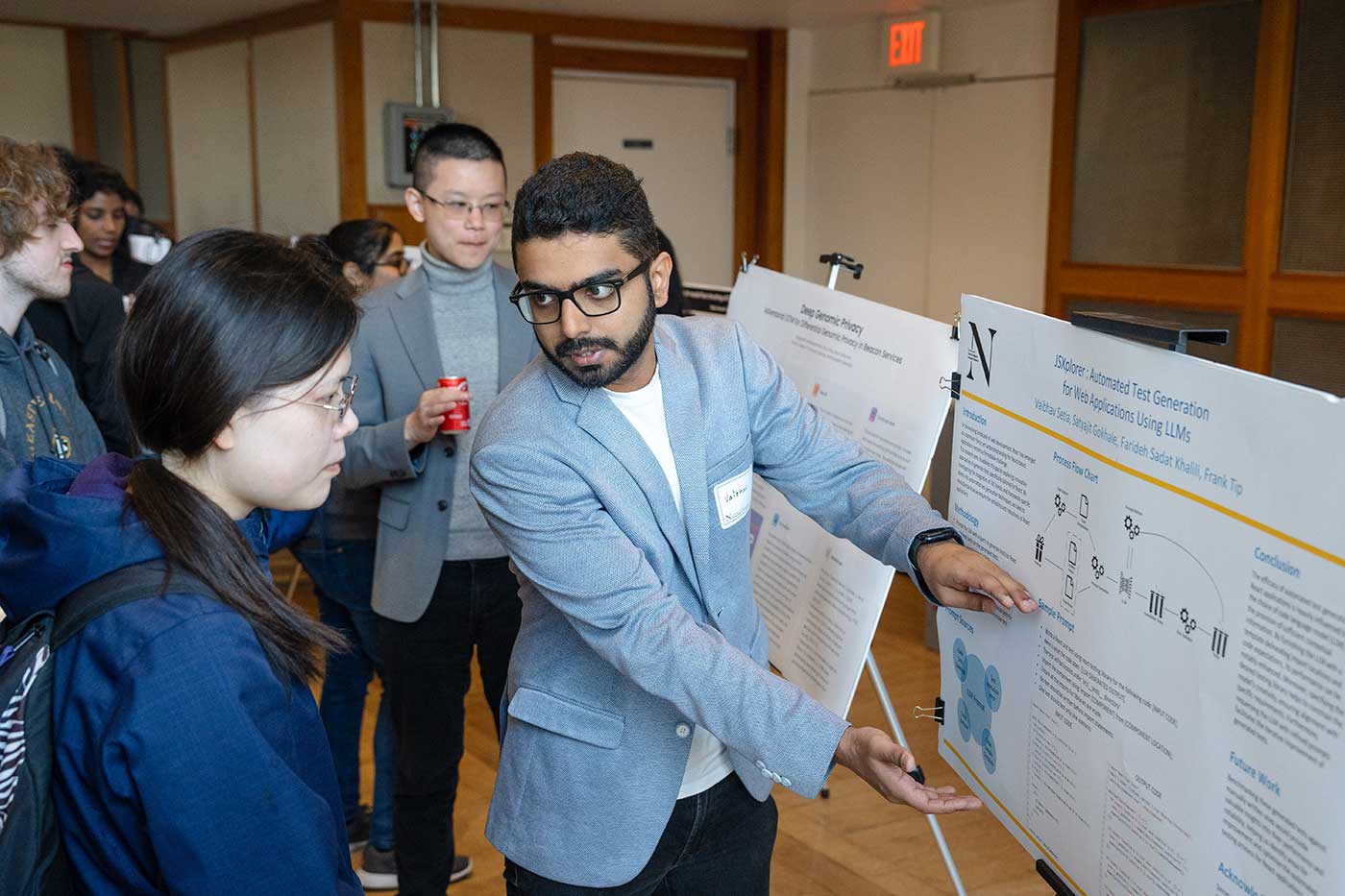 Vaibhav Setia gestures toward his research poster as he talks to another student