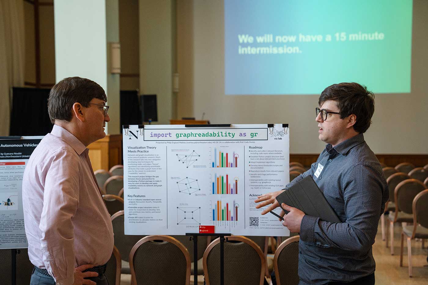Philip Englund Mathieu discusses his research poster with a Khoury faculty member