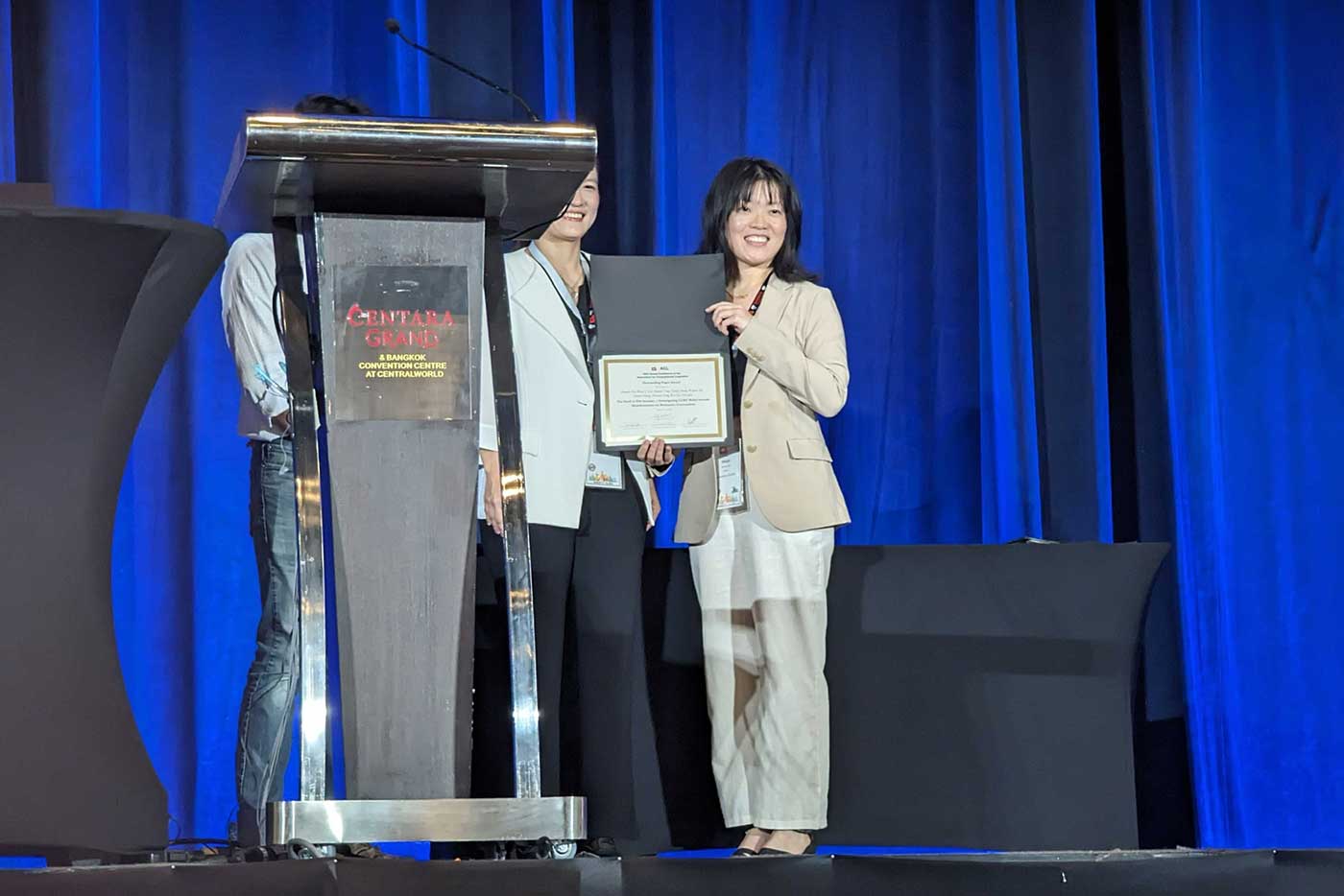 Weiyan Shi holds her certificate at the Annual Meeting of the Association for Computational Linguistics